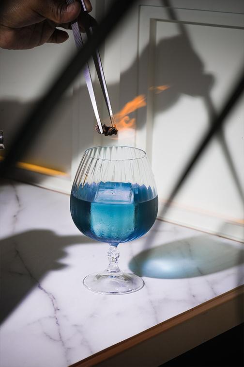 A blue cocktail being finished with a flame