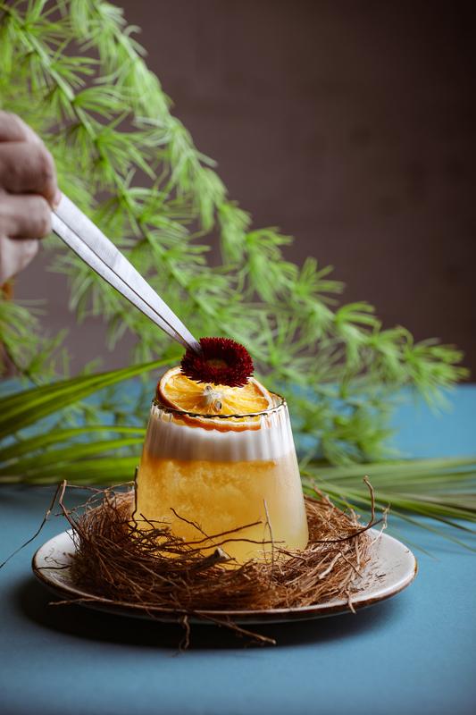 A cocktail garnished with a dried flower, served in a nest